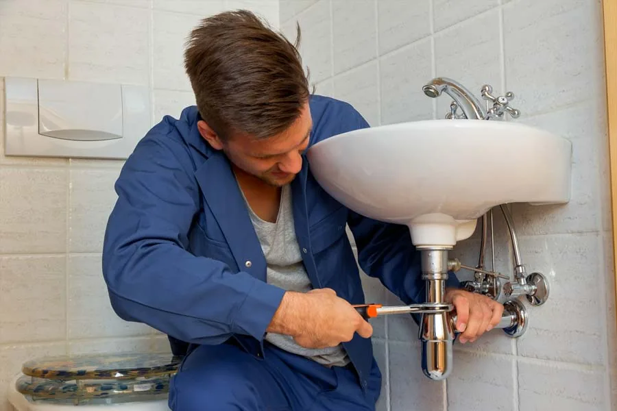 Symbolbild: Fachmann arbeitet an einem Badabfluss